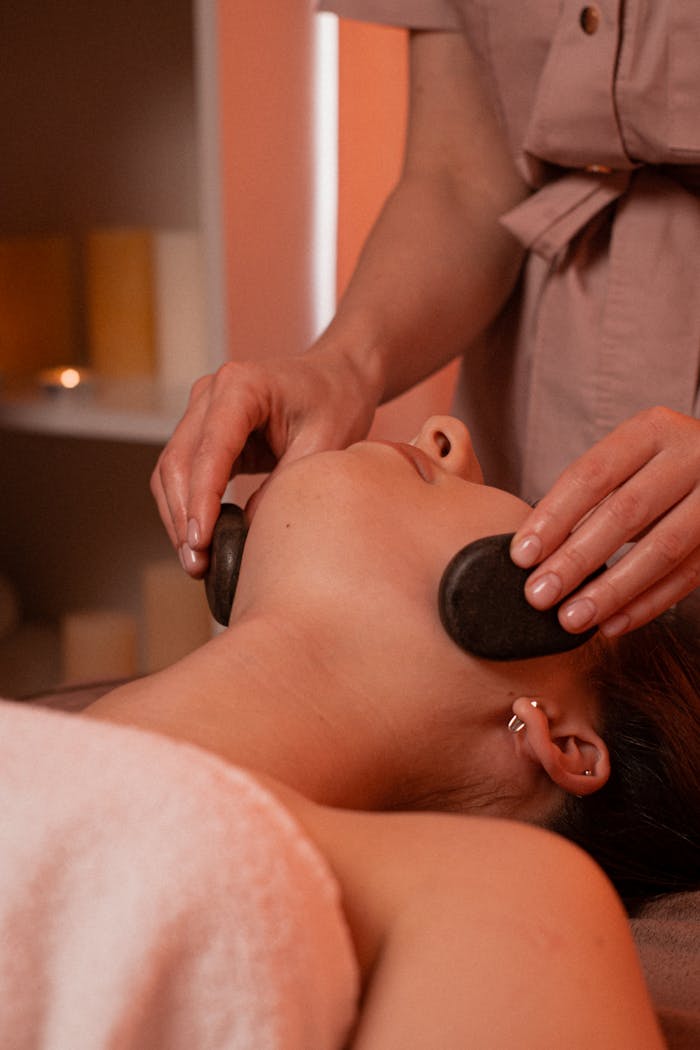 about-02 Relaxing stone massage on woman's face in a calm spa environment.