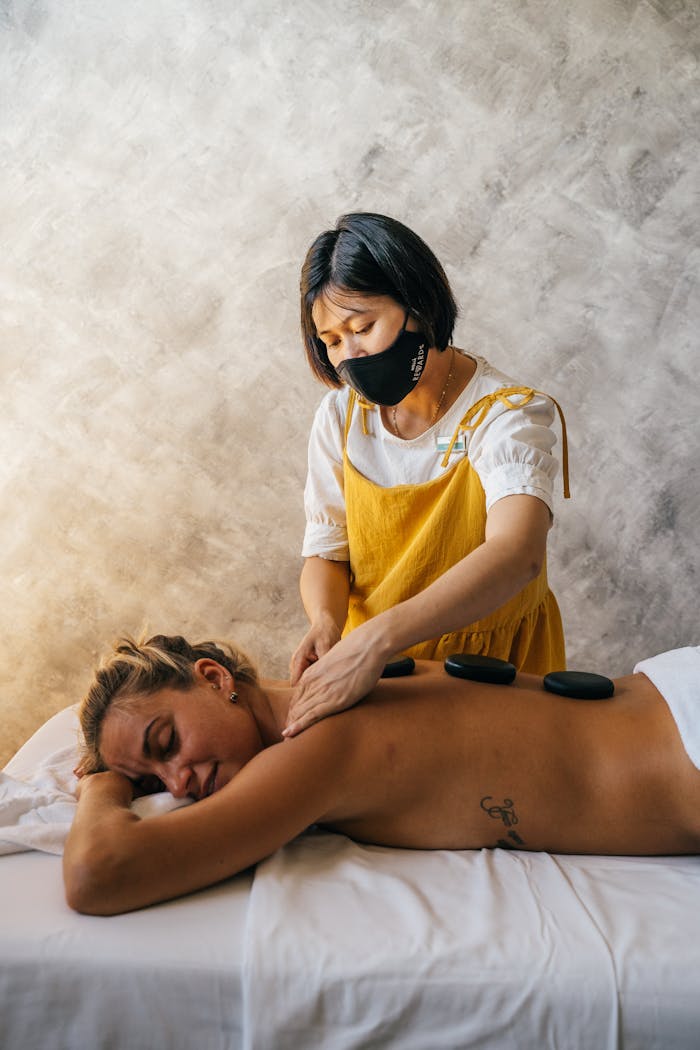 about-img A therapist providing a relaxing hot stone massage to a woman in a serene setting, promoting wellness.